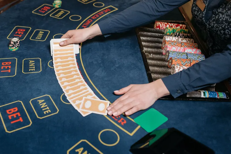 A casino dealer spreading playing cards across a gaming table