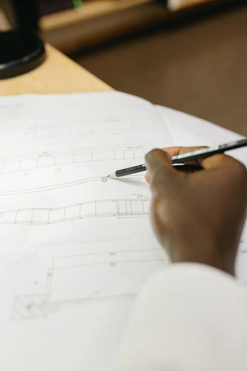 Detailed view of an architect's hand drafting a blueprint in a workspace setting