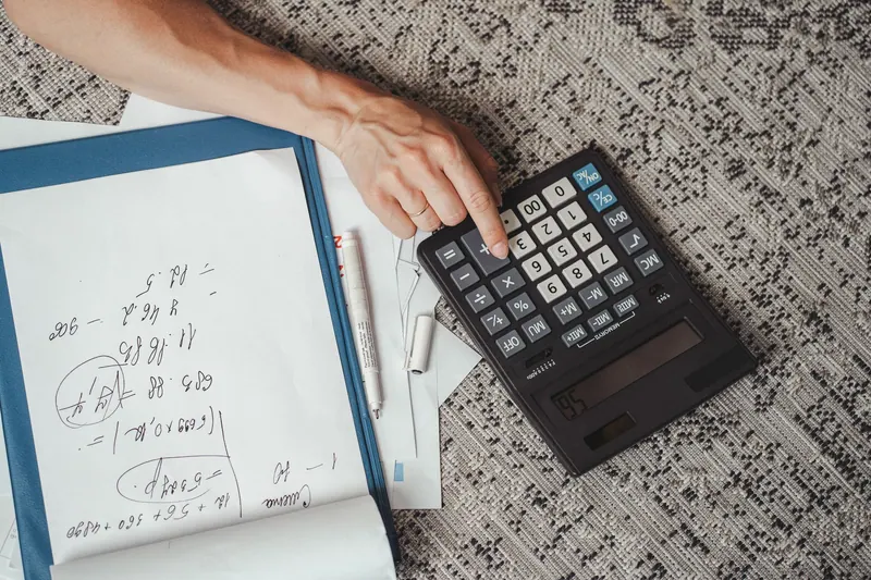 Hand using a large calculator on a desk