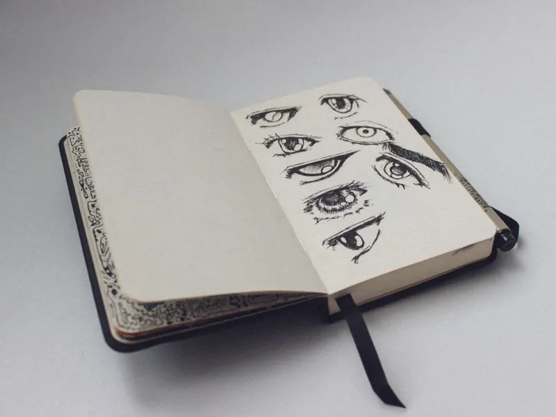 A sketchbook open to a page with artistic eye drawings, showcasing detailed sketches