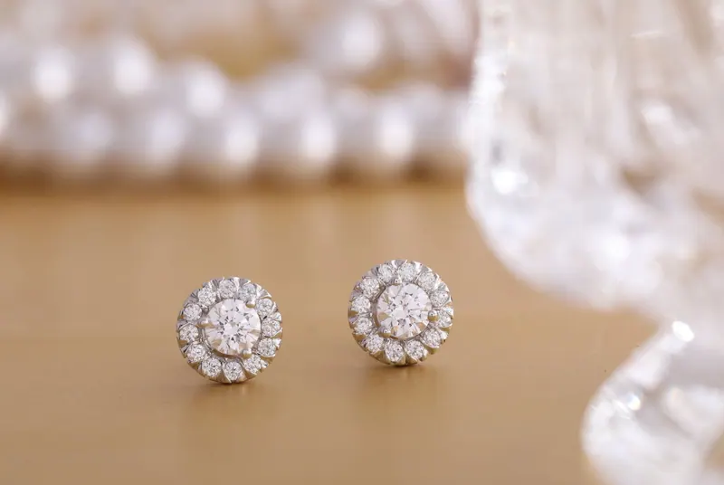 Close-up of round diamond earrings on a gold background, showcasing luxury and elegance