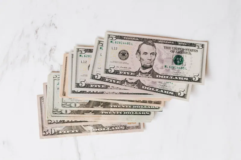 Top view heap of american dollar bills in different denominations placed on marble surface