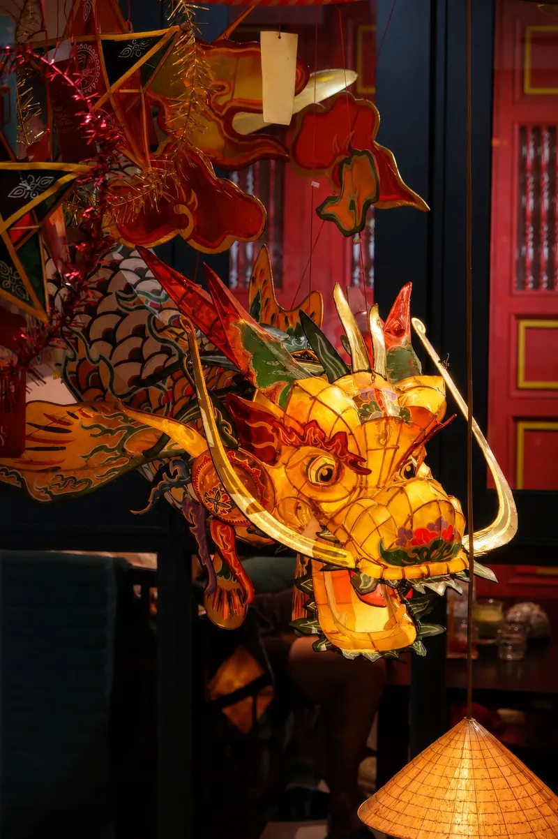 Colorful dragon lantern decor against an ornate red backdrop, celebrating Chinese culture indoors