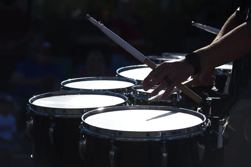 Close-up of a drummer skillfully playing multiple percussion drums outdoors