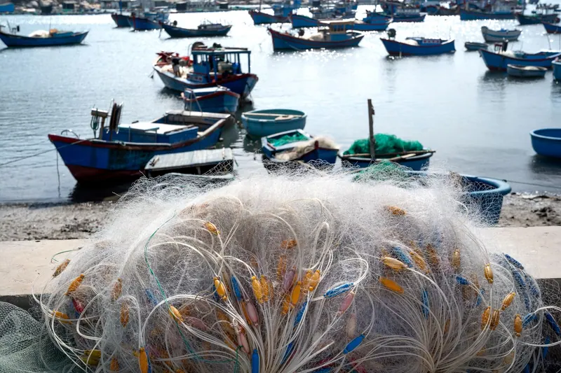 A scenic view of fishing boats and nets by the harbor under a bright day sky