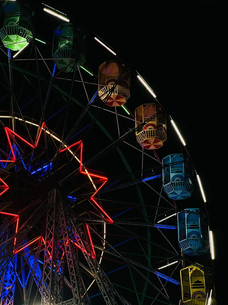 Colorful Ferris wheel glowing at night, showcasing bright lights and vibrant colors at a carnival