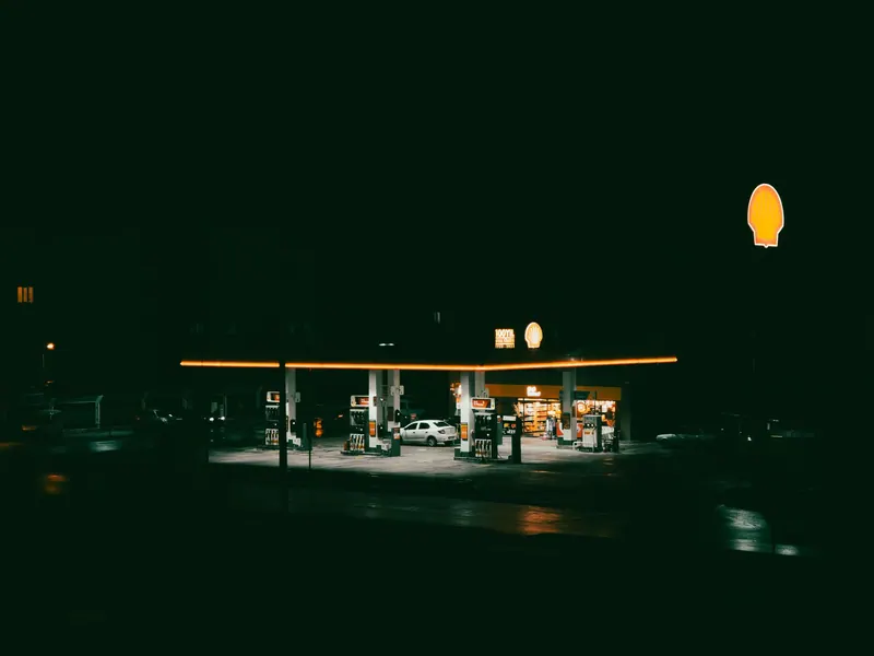 A brightly lit gas station at night, showcasing neon lights and empty pumps