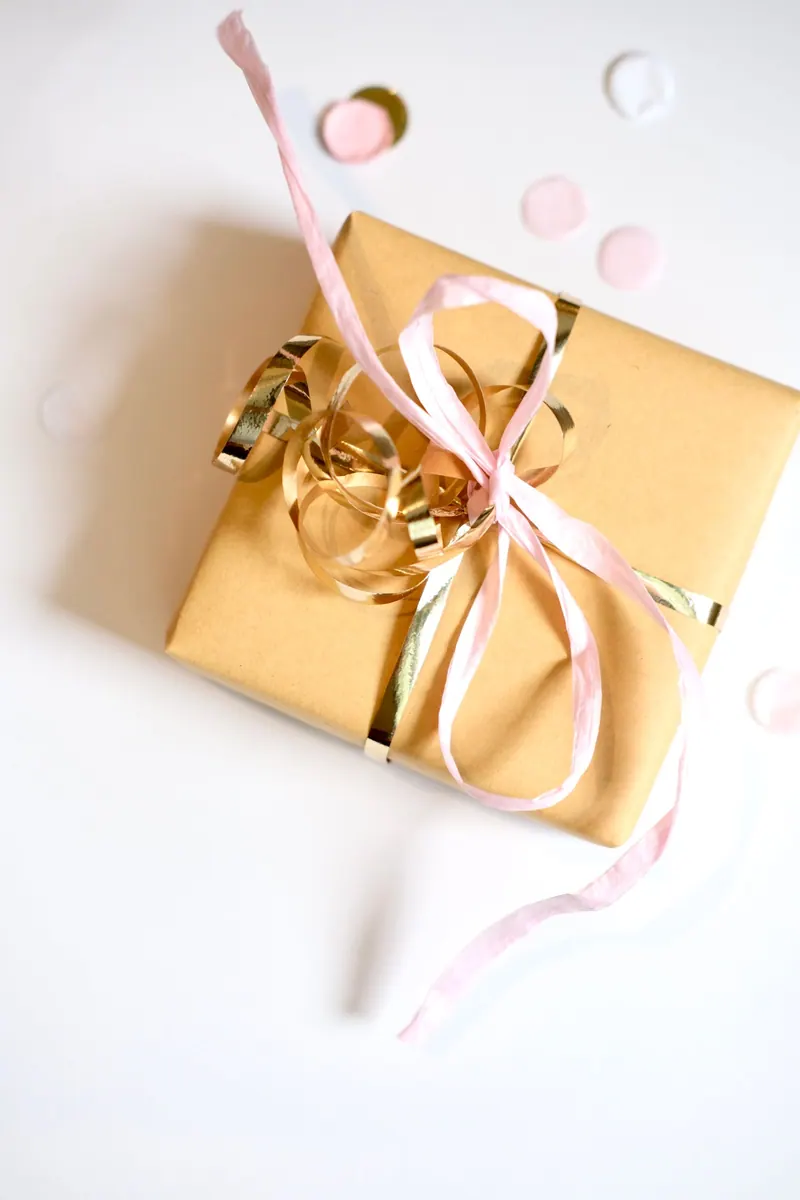 A stylish gold gift box with a pink ribbon