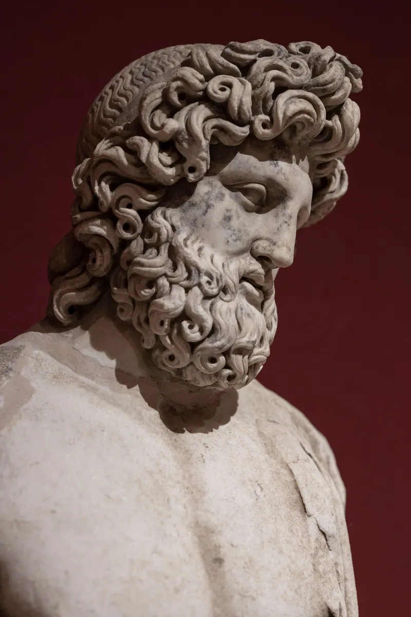 Close-up of an ancient marble statue depicting a Greek god with intricate details