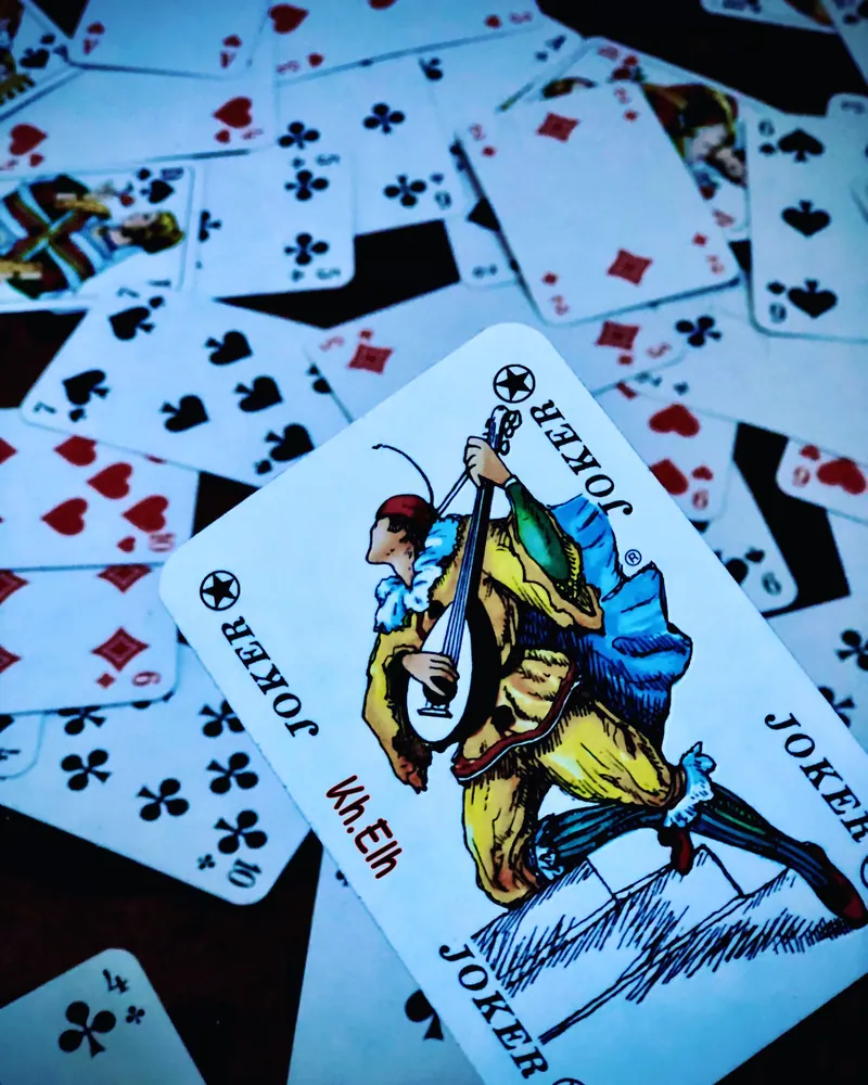 High angle view of scattered playing cards featuring a colorful joker card prominently.