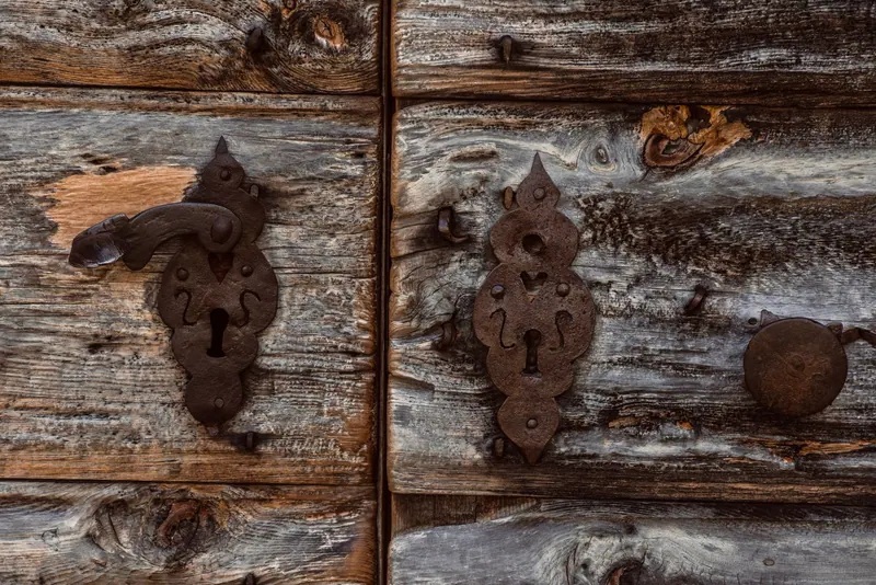 Close-up of an old wooden door featuring a rustic keyhole and vintage metal lock