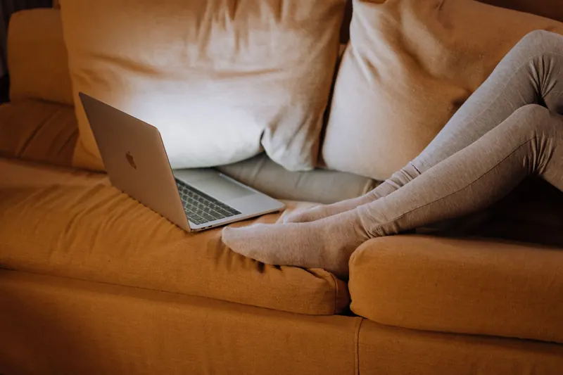 A person relaxing on a sofa using a laptop at home