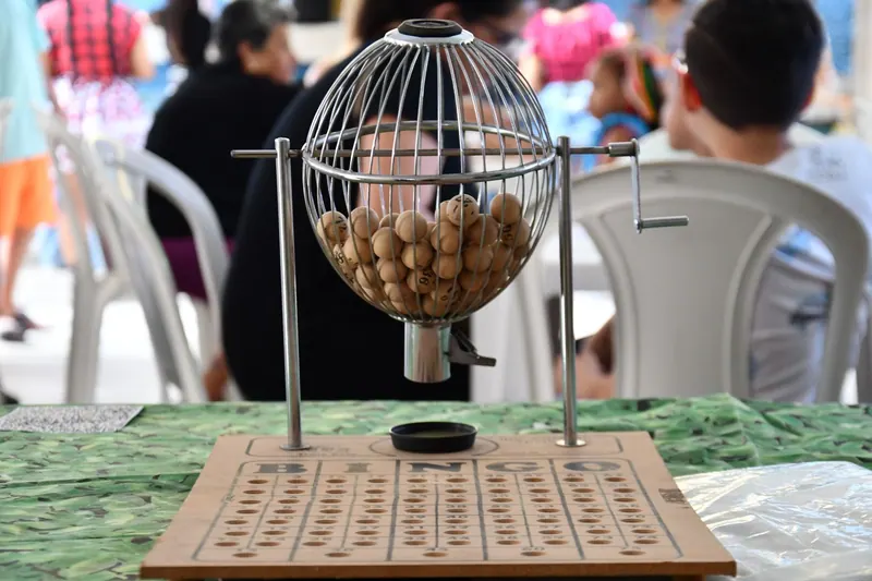 A bingo cage filled with numbered balls next to a board
