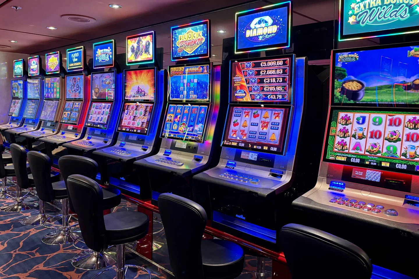 Rows of illuminated slot machine screens in an indoor venue