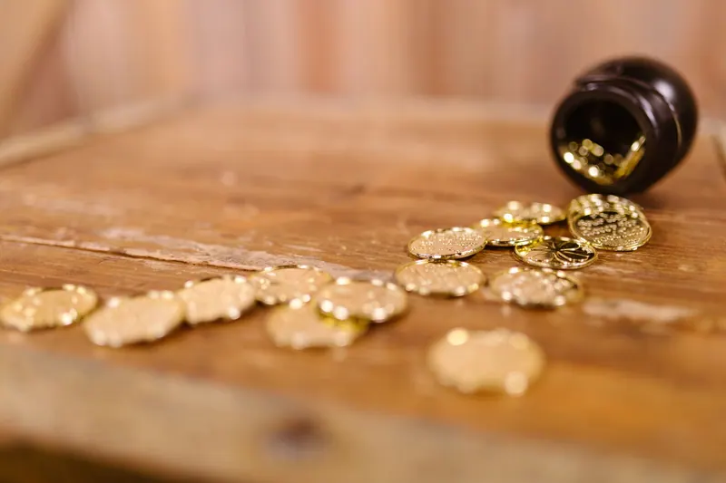 A pot of scattered gold coins on a wooden table