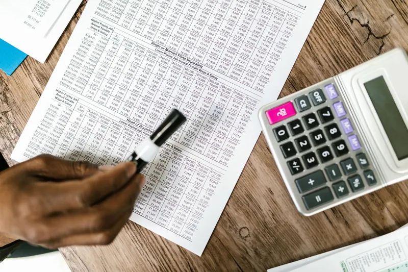 A hand marks entries in a printed numerical table