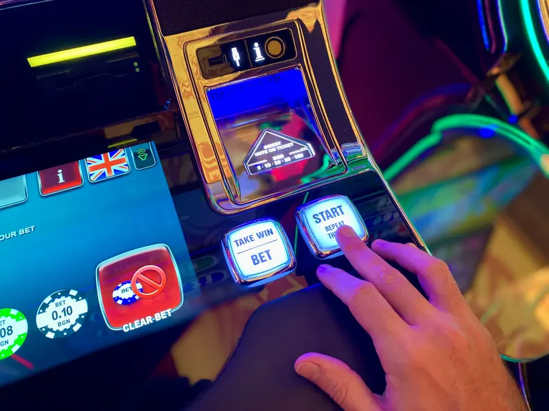 Hand using the button panel of a colorful slot machine interface