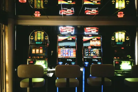 Three illuminated slot machines with empty chairs