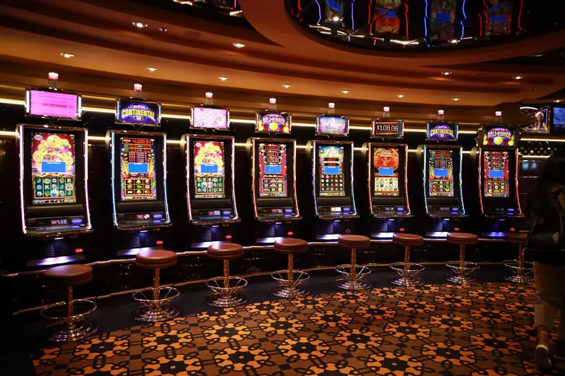 A row of luxury slot machines in a casino interior with plush stools, perfect for gaming enthusiasts